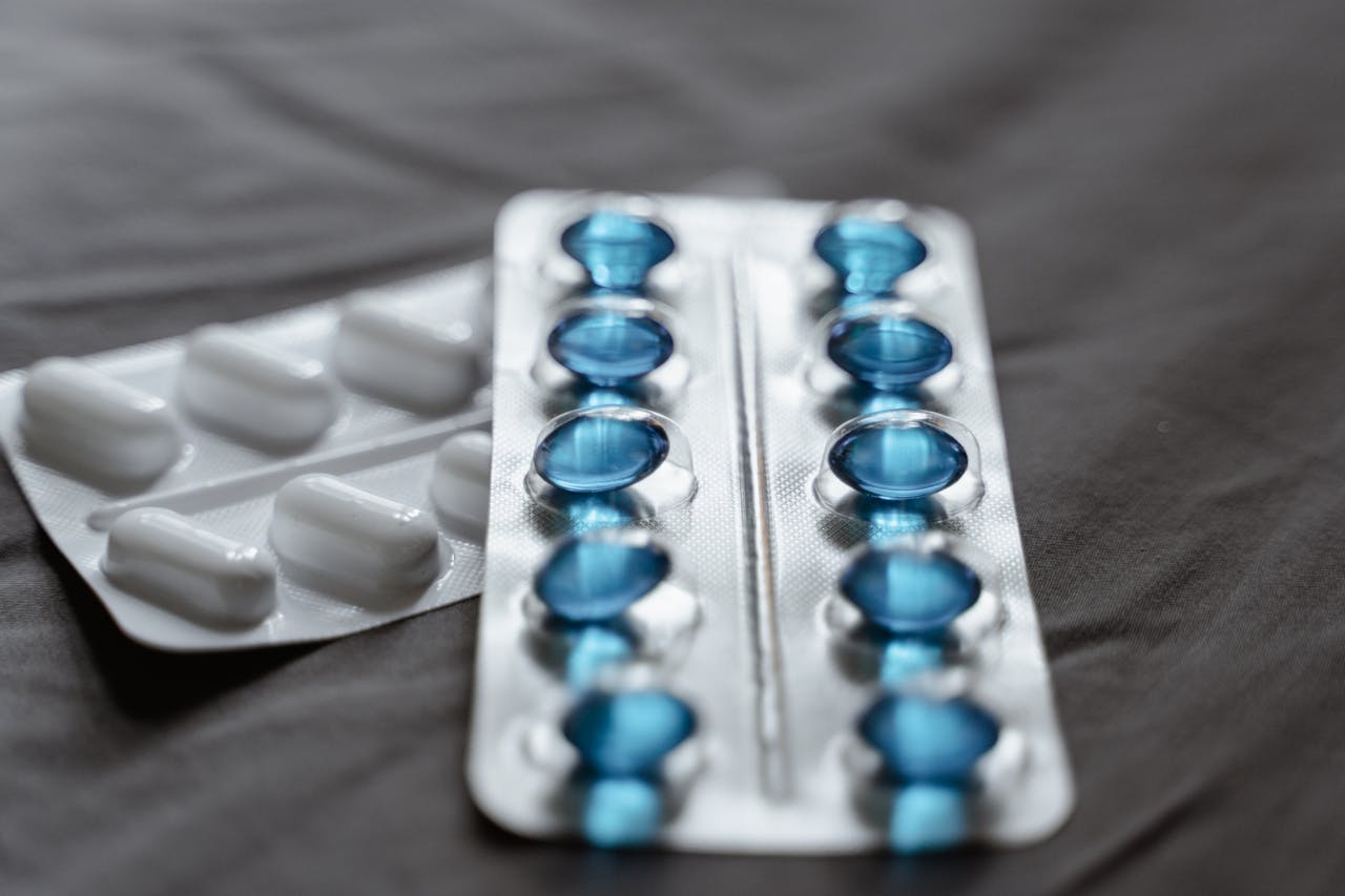 Detailed view of medication in blister packs showcasing blue softgel capsules and white pills.